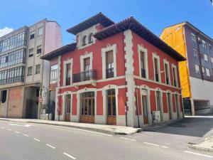 un bâtiment rouge et blanc sur le côté d'une rue dans l'établissement Apartamento el Ferreiro, à Grado