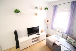 sala de estar blanca con TV de pantalla plana en Precioso apartamento en el Pirineo Aragonés, en Sabiñánigo