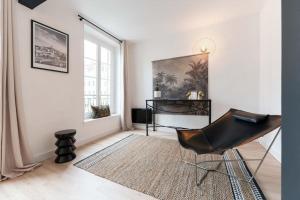 una sedia nera in una stanza bianca con finestra di Appart splendide Au Soleil à 2 pas Vieux-Port a Marsiglia