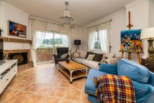 sala de estar con sofá azul y chimenea en Villa Mira Monda, en Monda