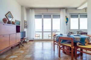 een woonkamer met een tafel, stoelen en ramen bij Blumele Lovely Sea View Apartment in Deiva Marina