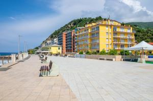 een bank op een promenade naast een geel gebouw bij Blumele Lovely Sea View Apartment in Deiva Marina