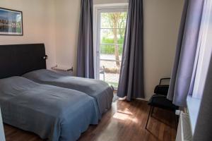 Nordgården Pension في Onsbjerg: غرفة نوم بسرير ونافذة كبيرة