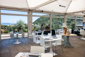 ein Restaurant mit Tischen und Stühlen und großen Fenstern in der Unterkunft A Point Porto Ercole Resort & Spa in Porto Ercole