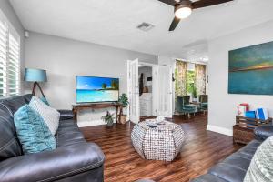 a living room with a couch and a flat screen tv at Tropical Waters Hideaway - Pool Tiki & Lounge in Pompano Beach