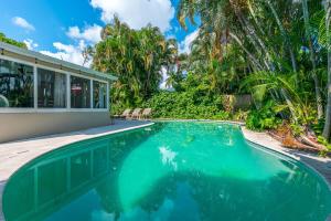 a swimming pool in front of a house at Private Oasis on Quiet Street! Pool + Tiki Hut! in Pompano Beach