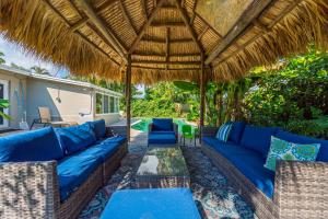 an outdoor patio with blue couches and a straw umbrella at Tropical Waters Hideaway - Pool Tiki & Lounge in Pompano Beach