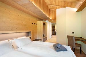 a bedroom with a white bed and a wooden ceiling at Agriturismo Bosco d'oro 2 in Livigno