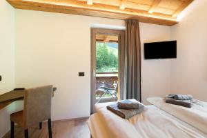 a bedroom with two beds and a desk and a window at Agriturismo Bosco d'oro 2 in Livigno