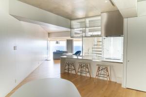 a kitchen with white cabinets and a counter with stools at 湘南OCEAN HOUSE in Koshigoe