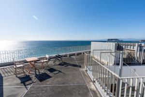 a balcony with a table and chairs and the ocean at 湘南OCEAN HOUSE in Koshigoe
