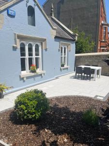 a blue house with a patio and a table at Wellington Cottage in Wexford