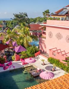 an aerial view of a resort with pink umbrellas and a pool at PinkCoco Uluwatu - Constant Surprises - for Cool Adults Only in Uluwatu