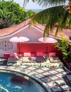 een zwembad met stoelen en parasols naast een zwembad bij PinkCoco Uluwatu - Constant Surprises & for Cool Adults Only in Uluwatu