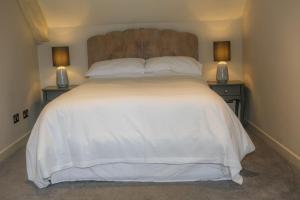 um quarto com uma grande cama branca com duas mesas de cabeceira em Cosy Modern Cottage - Wareham em Wareham