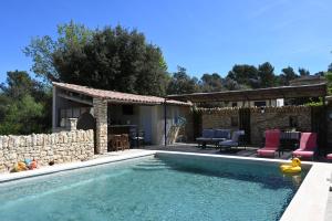 a swimming pool with a patio and a house at Gîte Bienvenue Chez Nous in Ménerbes