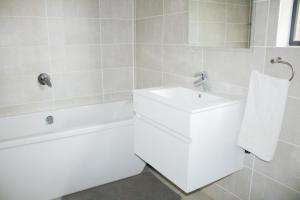 a white bathroom with a sink and a bath tub at 1517 The Blyde Crystal Clear 3 Bedroom Garden Beachfront in Pretoria +26 photos