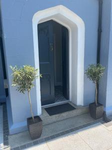 a blue building with two potted trees in front of a door at Wellington Cottage in Wexford