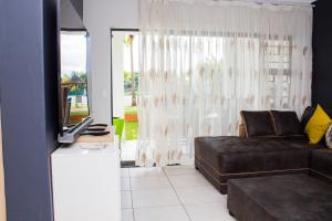 a living room with a couch and a television at 1517 The Blyde Crystal Clear 3 Bedroom Garden Beachfront in Pretoria