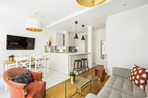 ein Wohnzimmer und eine Küche mit einem Sofa und einem Tisch in der Unterkunft Dulong - Luxury near Monceau & Wagram in Paris