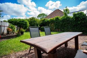 een houten picknicktafel in een tuin met 2 stoelen bij Appartement Atmospheria in romantische stolp in Warmenhuizen