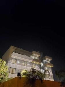 un grand bâtiment la nuit avec des arbres devant lui dans l'établissement Hotel The Golf 1, à Lucknow