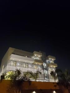 un grand bâtiment la nuit avec des arbres devant lui dans l'établissement Hotel The Golf 1, à Lucknow