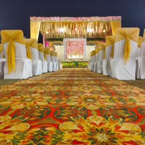 an aisle with white chairs and a colorful carpet at Hotel The Golf 1 in Lucknow