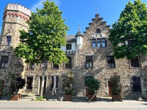Boutiquehotel Burg Adenbach & Alter Weinbau في باد نوينار آرفايلر: مبنى حجري قديم امامه شجرة