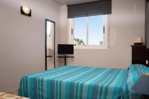 a bedroom with a bed with a striped blanket and a window at AT016 Piscina con césped, airco, playa a pocos pasos in Torredembarra +15 photos