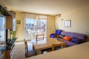 a living room with a table and a couch at AT016 Piscina con césped, airco, playa a pocos pasos in Torredembarra