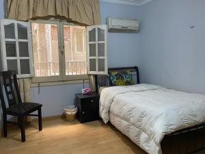 1 dormitorio con 1 cama, 1 silla y 1 ventana en Cozy private room @ SWEET HOME, en El Cairo