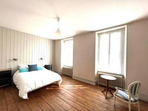 ein Schlafzimmer mit einem Bett, einem Tisch und zwei Fenstern in der Unterkunft Charmante charentaise in Saint-Jean-dʼAngély