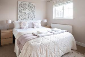 a bedroom with a white bed with two towels on it at Historic Malmesbury - Delightful home with parking in Malmesbury