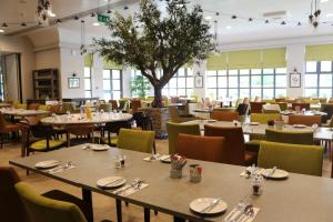 a restaurant with tables and chairs and a tree at The Woodlands Event Centre in Wyboston