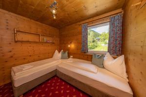 two beds in a wooden room with a window at Appartements Fürstauer in Saalbach Hinterglemm