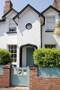 a white house with a green door and bushes at Bumblebee cottage Exmouth in Exmouth