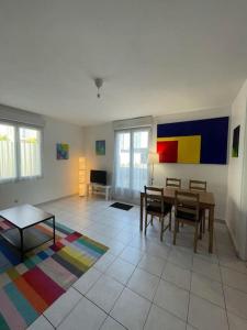 sala de estar con mesa y alfombra colorida en Maisonette parking privé gratuit, en Doué-la-Fontaine