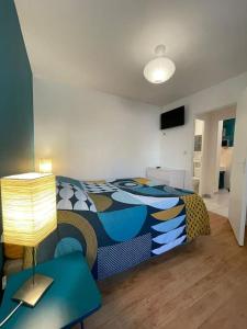 1 dormitorio con 1 cama y 1 mesa con lámpara en Maisonette parking privé gratuit, en Doué-la-Fontaine