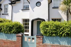 une maison blanche avec une porte verte et des buissons dans l'établissement Bumblebee cottage Exmouth, à Exmouth