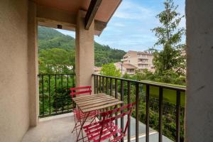 Duas cadeiras vermelhas e uma mesa na varanda em Alexandra Apartments em Digne-Les-Bains