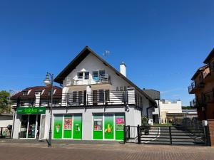 a white and green building with a balcony at AGAT Pokoje Gościnne Apartamenty in Pobierowo