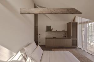 a white bedroom with a bed and a kitchen at Hill Palanga & SPA in Palanga