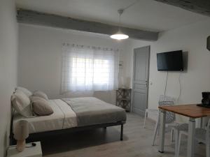 1 dormitorio con cama, mesa y TV en Studio Entier en Saint-Laurent-dʼAigouze