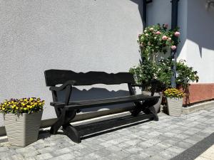 a black bench sitting next to two potted plants at Pokoje Gościnne AGAT in Pobierowo
