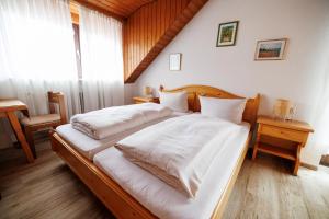 een slaapkamer met een bed met witte lakens en een raam bij Drexl Gasthof Shiro in Schondorf am Ammersee