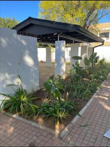 um pavilhão com telhado preto e plantas em Comfy Zone Apartment em Gaborone