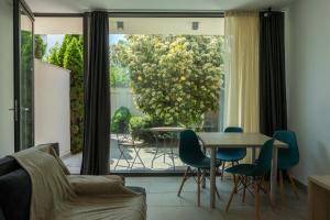 a living room with a table and chairs and a window at AIFEN Aparthotel - Apartamente pentru Toata Familia În Eforie Nord - cu Gradină Proprie, la 2 Pași de Plajă in Eforie Nord