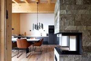 a dining room and kitchen with a stone fireplace at Alm-Lodges Montafon in Gargellen