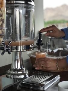 Maple house ladakh في ليه: تقوم المرأة بتقديم مشروب في الخلاط